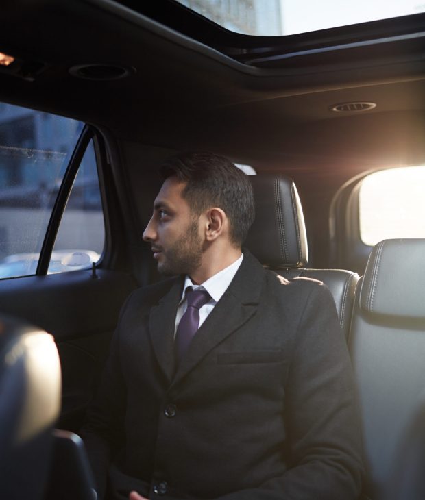 Portrait of successful Middle-Eastern businessman looking out of window of expensive luxury car